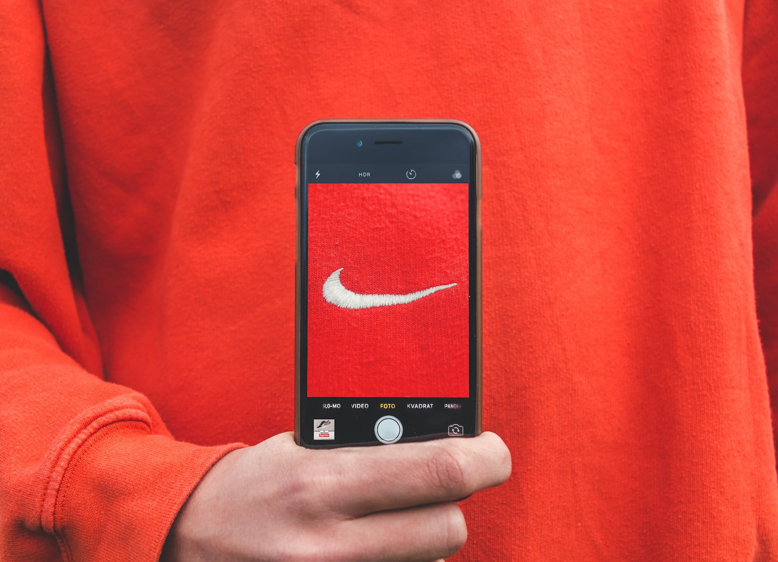 person holding iPhone taking picture on Nike label - branding